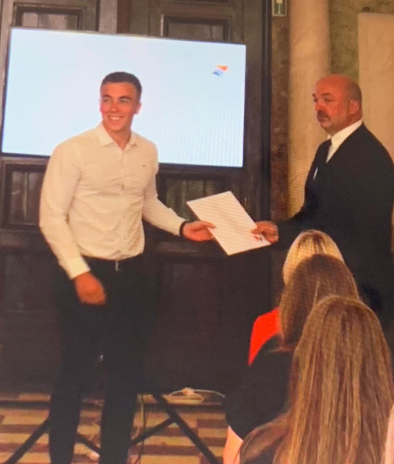 Mauro krijgt zijn diploma van het middelbaar uit handen van de directeur.